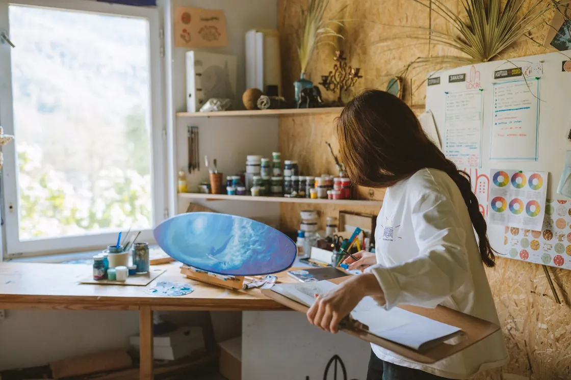 Artista trabajando en su taller con pinturas y pinceles